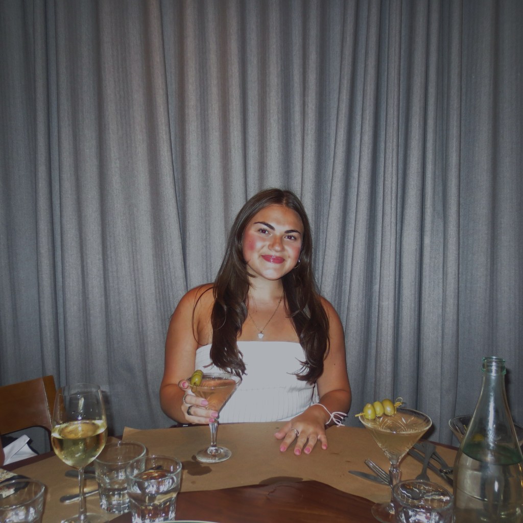 Marissa Romano sitting at a table and holding a martini glass.